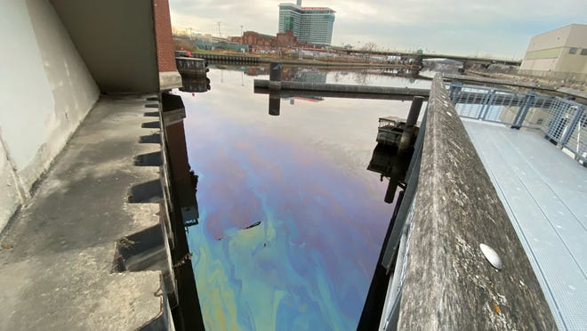 Oil is seen in the Menomonee River at the Emmber Lane canoe launch near West 13th Street. In what it says was an error, manufacturing giant Komatsu spilled 400 gallons of used oil into a storm sewer, which drained into the Menomonee River.