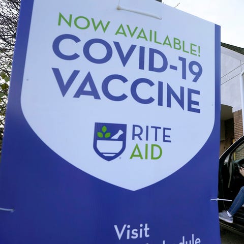 A woman is parked near a COVID-19 vaccine sign as 