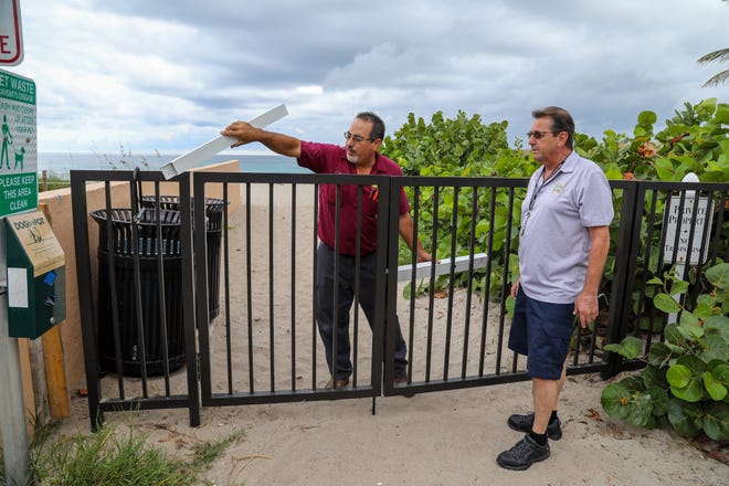John Rivera, left, of Sunshine Safe and Lock and Town of Palm Beach project coordinator Warren Golde discuss plans for new lock on gate that allows access to the beach at the intersection of Root Trail and North Ocean Boulevard last month.