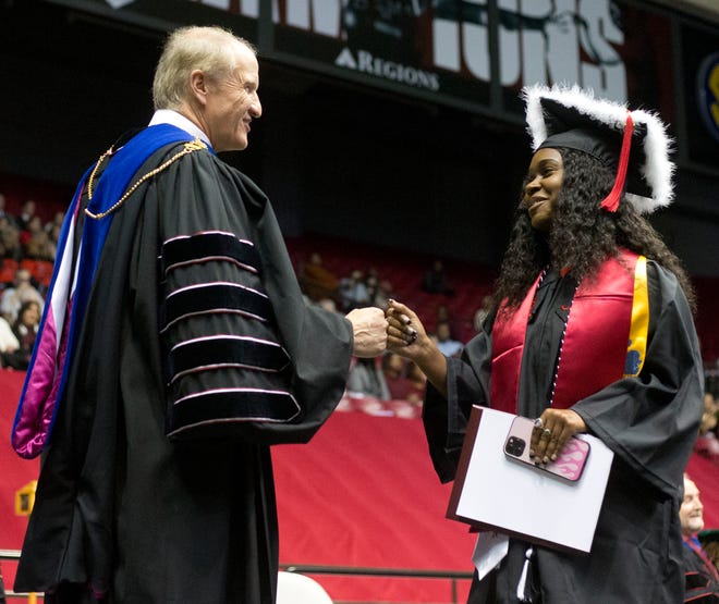 University of Alabama President  Stuart R. Bell gives a fist-bump to a graduate as she walks across the stage at Coleman Coliseum on Saturday Dec. 11, 2021. [Photo/Will McLelland]
