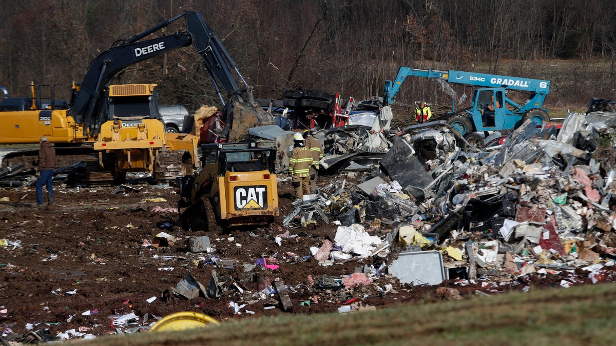 People look around the candle factory where workers were killed when a tornado struck Friday evening.  Dec. 11, 2021