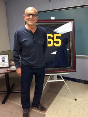 Roxbury football coach Jim Fiorello poses with a No. 65 jersey, which was retired in honor of Lenny Perfetti in 2014. Perfetti died from cancer at age 22.