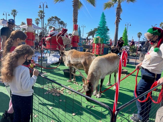 Reindeer handler Gayle Phelps, at right, talks to visitors about her charges, Dancer and Dasher, at the Ventura Harbor Village on Saturday.
