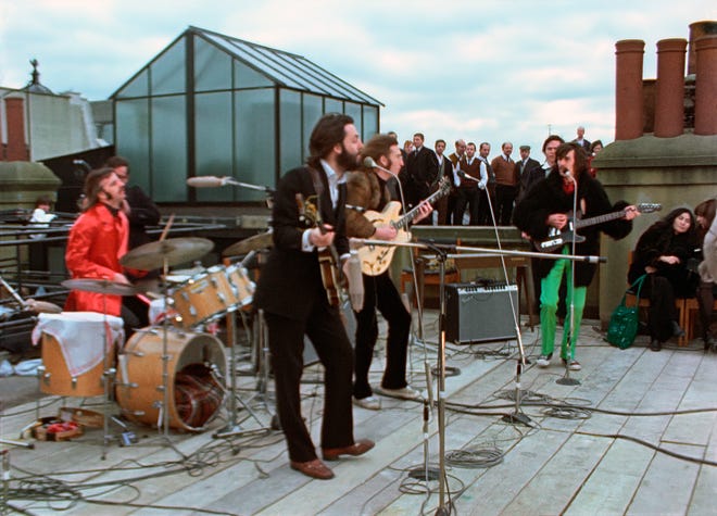 Ringo Starr, Paul McCartney, John Lennon and George Harrison, with Yoko Ono, seated right, in a rooftop scene from the Disney+ miniseries “The Beatles: Get Back.”