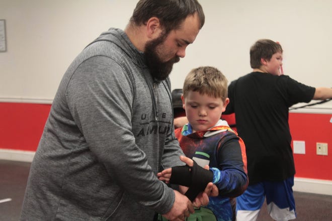 Jace Shingary, 7,  receives help wrapping his hands from his father and coach Shane at boxing practice.