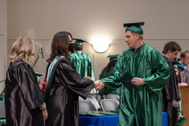 Danielle White, the Excel Center school director shaking hands with Joseph Vanderwall, a recent Excel Center graduate, after receiving his diploma at the Excel Center graduation, on Thursday, Dec. 9, 2021, at the Kossuth Street Baptist Church, in Lafayette.