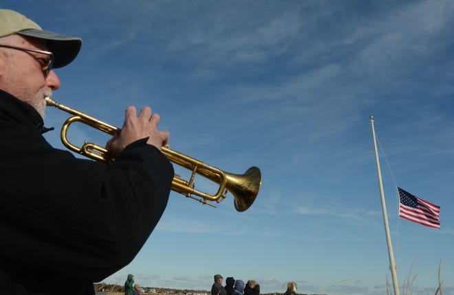 Bugler Joe Mongelli plays taps after a memorial wreath was tossed into the sea at Bass River Beach, where a small group gathered with WWII veterans at the memorial stone to observe the 80th anniversary of the attack on Pearl Harbor.