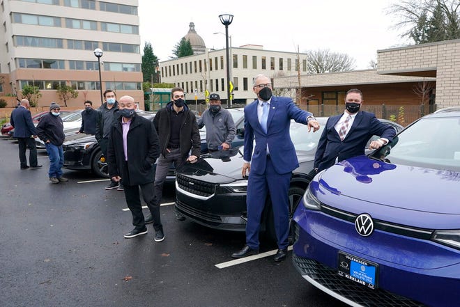 Washington Gov. Jay Inslee, second from right, poses for a photo, Monday, Dec. 13, 2021, with car dealership representatives who drive electric vehicles to a news conference in Olympia, Wash. Inslee announced several climate-related proposals for the 2022 legislative session, including a plan to offer rebates on the purchase of new and used electric vehicles for qualified buyers. (AP Photo/Ted S. Warren)