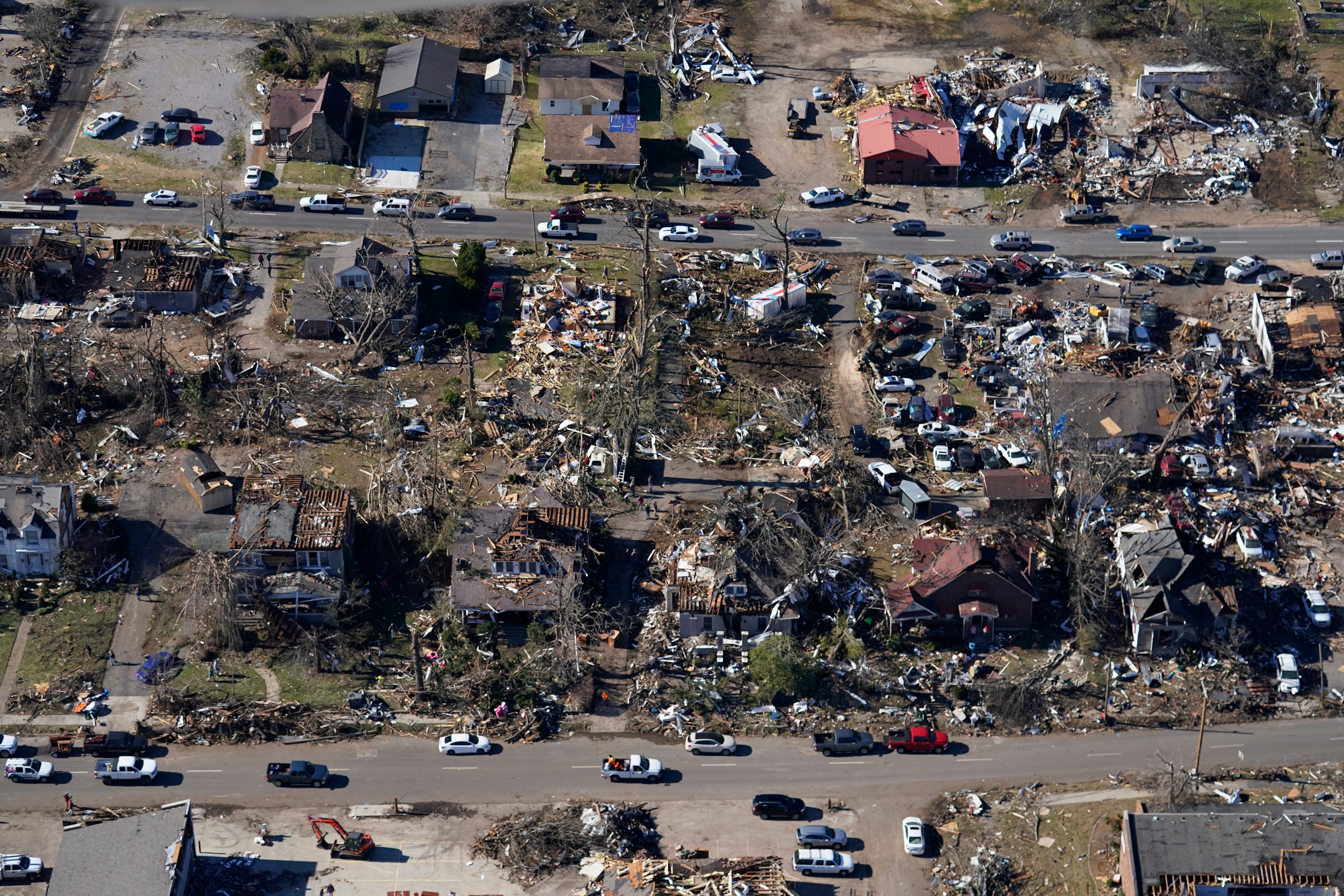In this aerial photo, cars drive past destroyed homes in the aftermath of tornadoes that tore through the region, in Mayfield, Ky., Sunday, Dec. 12, 2021.