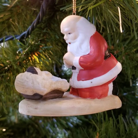 A ceramic ornament of Santa Claus kneeling by Jesu