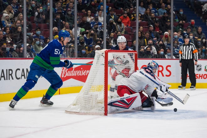 Dec 14, 2021; Vancouver, British Columbia, CAN; Columbus Blue Jackets defenseman Zach Werenski (8) looks on as goalie Elvis Merzlikins (90) makes a save on Vancouver Canucks defenseman Tyler Myers (57) in the first period at Rogers Arena. Mandatory Credit: Bob Frid-USA TODAY Sports
