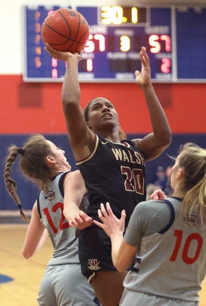 Walsh's Sha Carter splits the defense of Malone’s Emma Kallas (left) and Alexis Hutchison during a game last month.
