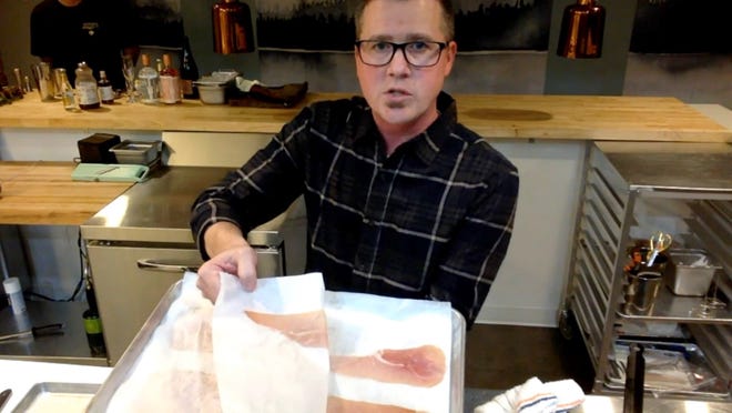 Doug Hewitt, executive chef at Freya, shows ham, laid out between paper on cooking sheets, that will be turned into 'crispy ham.'