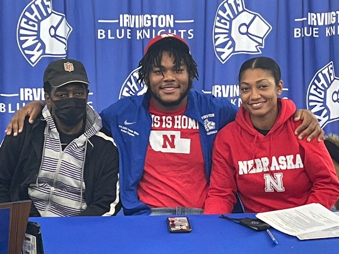 Justin Evans-Jenkins (center) commits to Nebraska with grandfather James C. Evans (left) and mother Seanette Evans (right).
