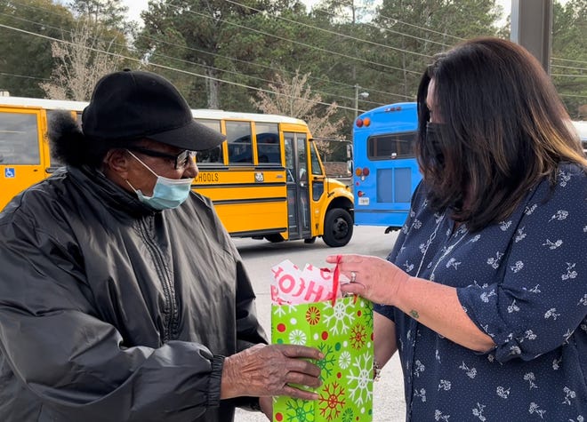 Tanya Thompson, right, of Augusta, Ga., presents a gift of $300 in cash and gift cards to her neighbor and Tutt Middle School crossing guard Louvenia Gray, left, on Wednesday, Dec. 15, to lift Gray's spirits after the recent armed robbery she was a victim of.