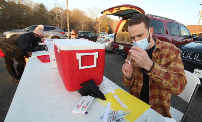 Pharmacist intern Graham Sprinkles prepares a dose of the Pfizer vaccine as free vaccination shots were offered in the parking lot of Mt. Zion Restoration Church on Crescent Lane in Gastonia early Thursday morning, Dec. 16, 2021.