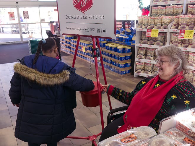 DeNiyah Jordan, 7, of Kent makes a donation at the Kent Acme Dec. 12 as Bell Ringer Candiy Lee holds the bucket steady for her.