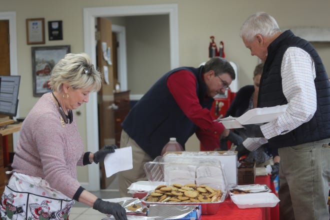 (From left) Tina Still, Bob Still and Bill Plowden pack meals for people who donated toys Thursday.