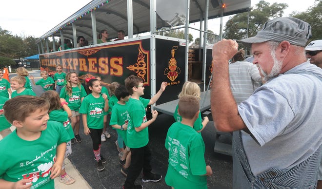 Lake Helen resident Alan Cooke, owner of Butler's Express, welcomes aboard St. Barnabas Episcopal School students for a ride on the "train" in DeLand on Wednesday, Dec. 15. The train generally stays in the smaller of the sister cities and is used for Christmas light tours in December.