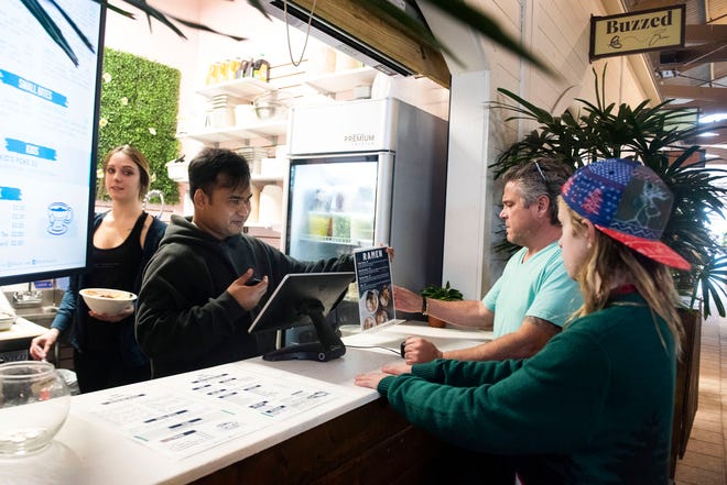 Bluefin Poke owner Bom Barnard takes a lunchtime order from customers Buddy Cummings and his son, Cruz, on Friday at the new downtown Pensacola restaurant. Bluefin Poke is the latest addition to The Garden at Palafox + Main.