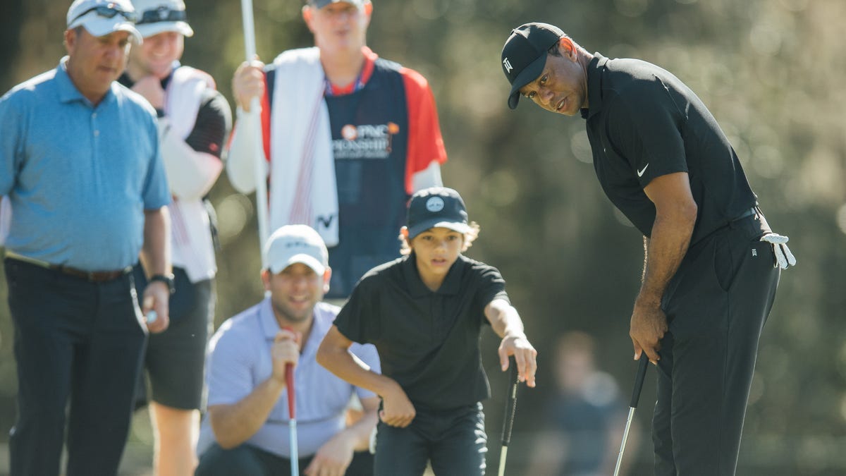 Tiger Woods lines up his putt on the ninth green as son Charlie looks on during a pro-am round of the PNC Championship.