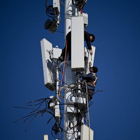Workers are seen on a 5G tower at Shougang Park, o