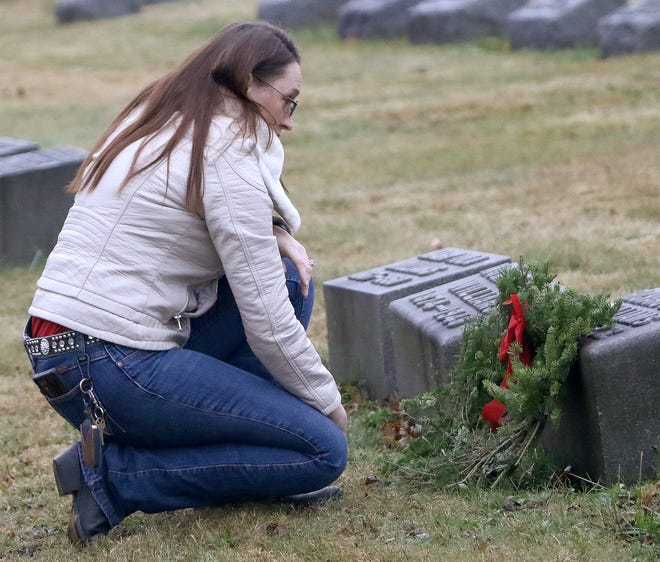 Retired Air Force Staff Sgt. Kat Hamlett pauses for a moment Saturday, Dec. 18, 2021, after placing a wreath on the grave of a veteran as part of the annual Wreaths Across America program at the Alliance City Cemetery.