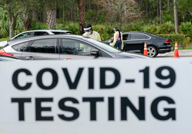 Healthcare workers get information from people lined up to be tested at a COVID-19 testing site in Palm Beach Gardens, Fla. on Dec. 20.