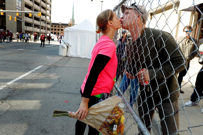 Ešlija Dankana no Vudhavenas saņem ziedus un skūpstu pāri žogam no drauga Bila Hendersona pēc tam, kad viņa pabeigs maratonu 44. ikgadējā Detroitas brīvās preses maratona laikā Detroitā svētdien, 2021. gada 17. oktobrī.