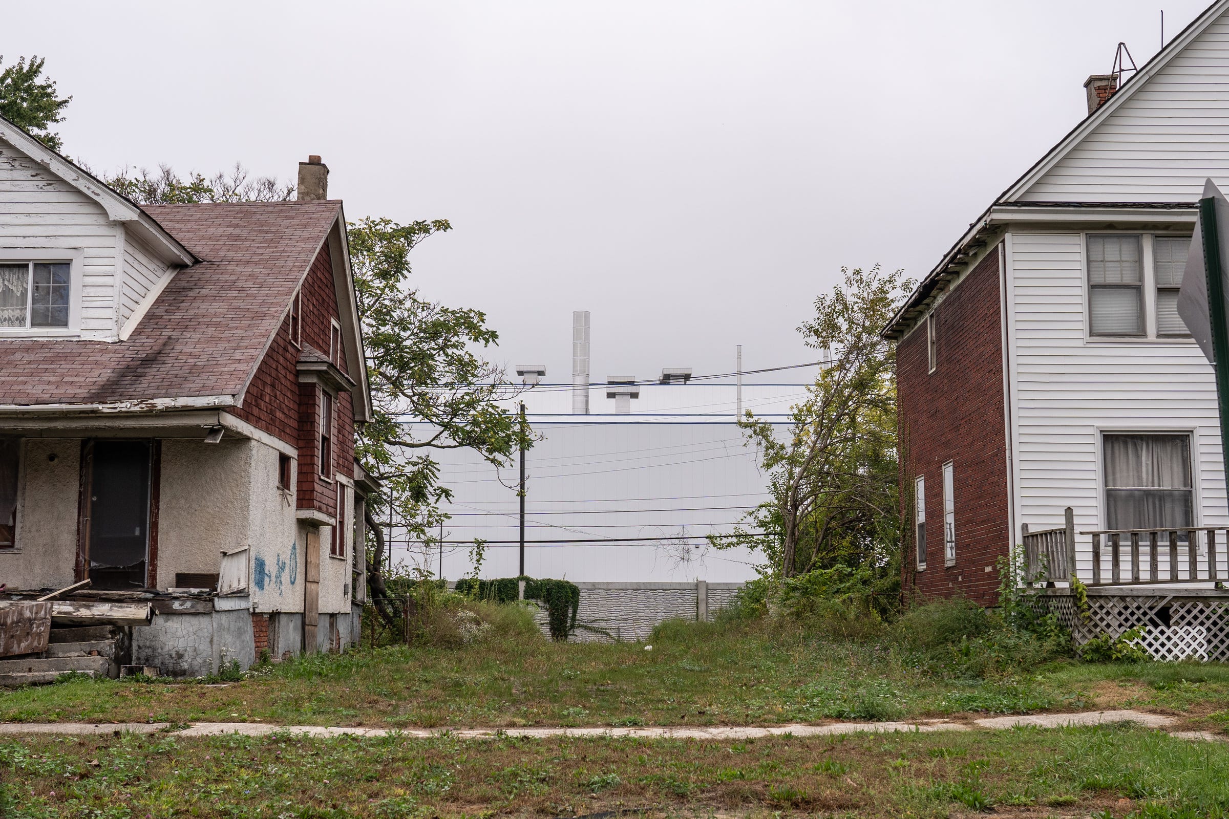 A section of the Stellantis Mack Assembly Plant on Detroit's east side peeks through the backyard of homes along Beniteau Street on Monday, Oct. 4, 2021.