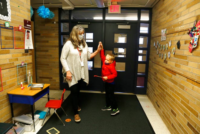 Seorang anak TK memberikan tos kepada pekerja sosial Deb Doyle setelah dia menyelesaikan tugas di sekolah dasar di Paw Paw, Michigan, pada Kamis, 2 Desember 2021. Tugas tersebut -- dengan cepat menginjak serangkaian jejak kaki di lantai di lorong sekolah -- dimaksudkan untuk membantunya melewati awal hari yang sulit.