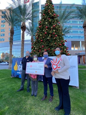 A group of people stands outside of the Phoenix Children's Hospital with a fund check donated by Peter Piper Pizza on Dec. 20, 2021.