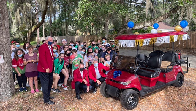 The Red Coats — former chairpersons of The Players Championship — deliver a new six-seater golf court for use at Catholic Charities' Camp I Am Special.