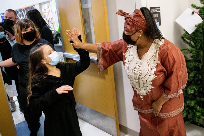 Erica Austin high fives the fifth-grade students who presented a Kwanzaa celebration at Enos Elementary School in Springfield on Wednesday. [Justin L. Fowler/The State Journal-Register]