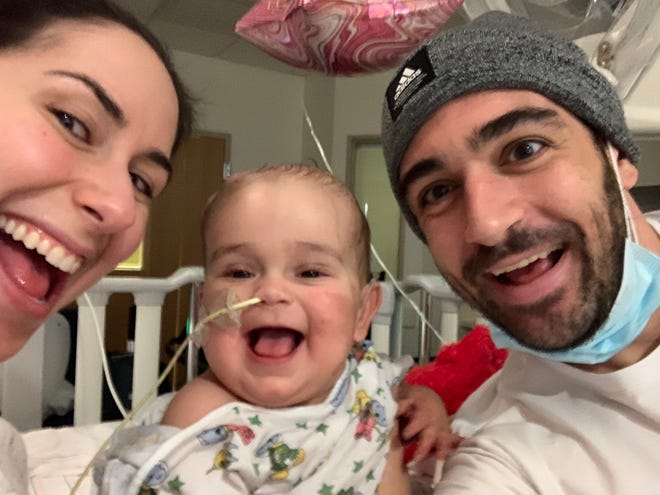 Rachel Ensign (left) and Andrew Kaczynski smile for the camera next to their daughter, Francesca, who died on Christmas Eve 2020. The parents have been public about their grief on social media, and have channeled those emotions into raising money for pediatric cancer research.