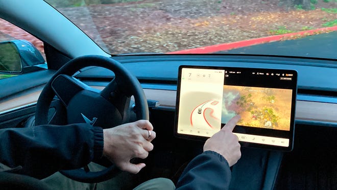Vince Patton, a new Tesla owner, demonstrates on Dec. 8, 2021, on a closed course in Portland, Ore., how he can play video games on the vehicle's console while driving. Under pressure from U.S. auto safety regulators, Tesla has agreed to stop allowing video games to be played on center touch screens while its vehicles are moving.