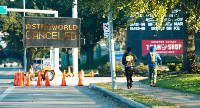 Mensen lopen langs een bord met de aankondiging van de annulering van Astroworld op 6 november 2021 in Houston.  De 10 mensen die stierven in de grote menigte op het muziekfestival stierven door compressieverstikking, zeiden functionarissen.