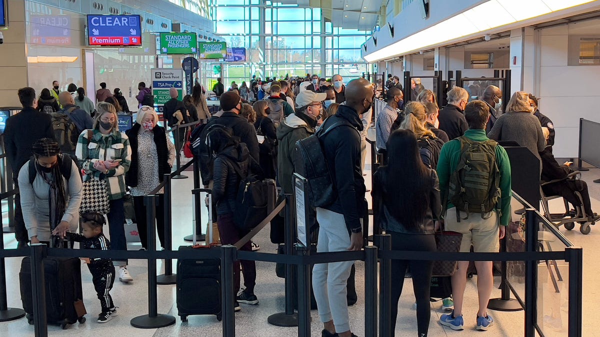 Travelers stand in line at a security checkpoint at Washington National Airport (DCA) in Arlington, Virginia, on November  24, 2021.