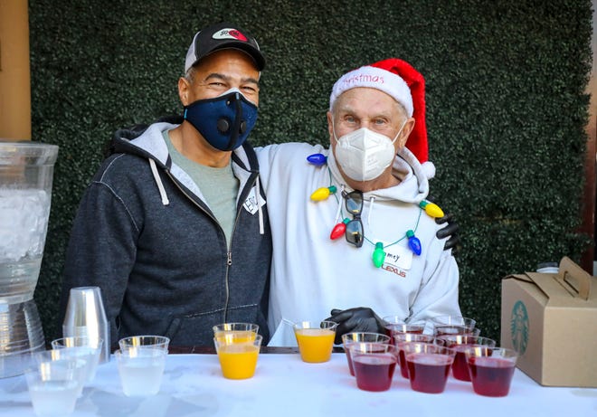 Volunteers Eric Mack (left) and Jamey Miller pose for a photo together while volunteering to serve at the beverage table at Oscar’s, Saturday, Dec. 25, 2021, in Palm Springs, Calif. 
