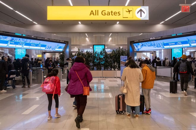 Travelers walk to a security check point at LaGuardia Airport in New York on Dec. 24, 2021. On Christmas Eve, airlines, struggling with the omicron variant of COVID-19, have canceled over 4,000 flights globally. (Yuki Iwamura/AFP via Getty Images/TNS)