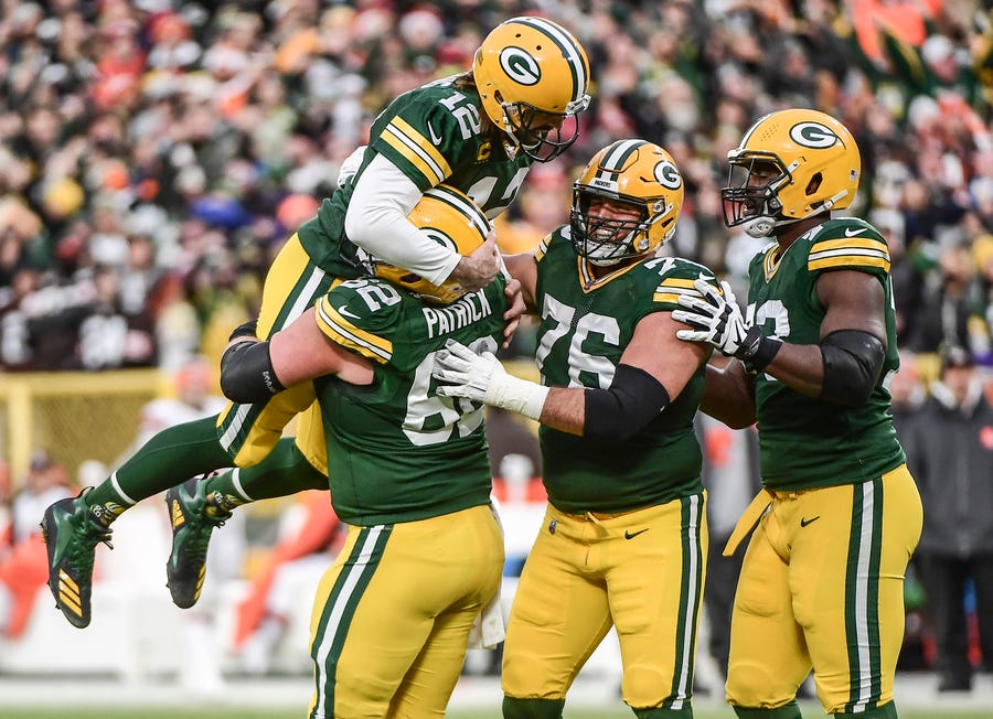 Green Bay Packers quarterback Aaron Rodgers is lifted up by guard Lucas Patrick after setting the franchise record for most passing touchdowns.