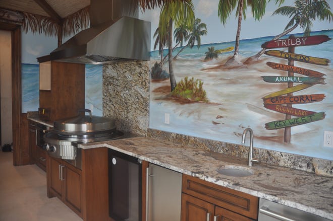 The third floor features a cabana room. An artist hand painted the walls with tropical beach scenes. The stone grill is used for everything from making pizza and steak to Asian meals. Bifold glass doors lead to a terrace that overlooks the canal and the Caloosahatchee.