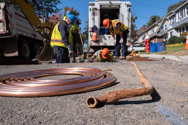 Suez utility workers replacing an old lead service line, seen at right, with new copper line, coiled at left. Service lines connect water mains with homes and businesses.