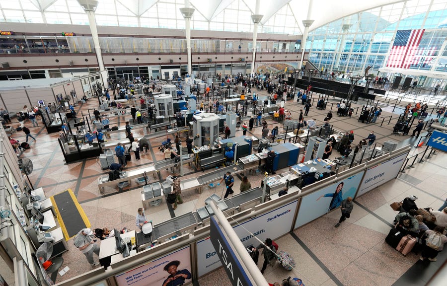 Travelers queue up at the south security checkpoint in the terminal of Denver International Airport on Dec. 26. Airlines canceled more than a thousand flights, citing staffing problems tied to COVID-19.