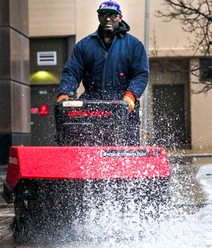 Michael Jones, an AAP Properties worker, uses a snow sweeper Tuesday in front of 1000 N. Water St. in Milwaukee.