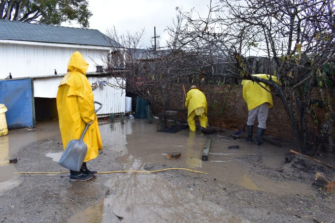 A family attempts to clear out floodwater from their backyard near San Juan Grade Road, Salinas, Calif., on Dec. 27, 2021.