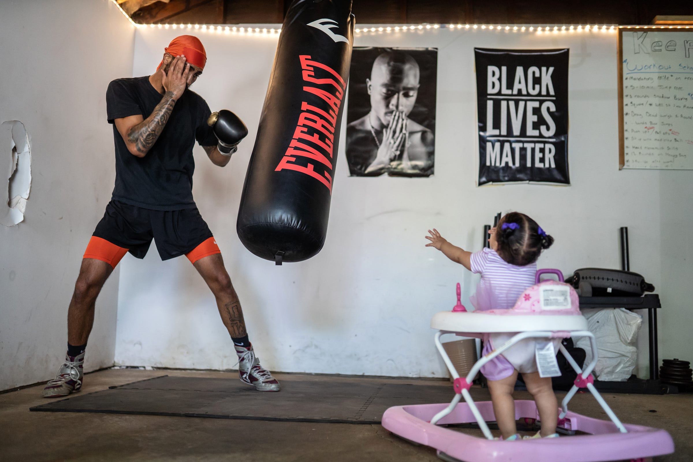 Dwayne Taylor, of Lincoln Park, does a timed drill while training for his professional boxing debut in his garage as his daughter Ari Taylor watches from her walker on Tuesday, June 15, 2021. "I'm not just doing it for myself. I'm doing it for my whole family - for my kids now," Taylor said. He wants to give them a different life with more options. "I'd like to break the cycle. The first one to change something. My family's been struggling for a long time. It's bigger than me now."