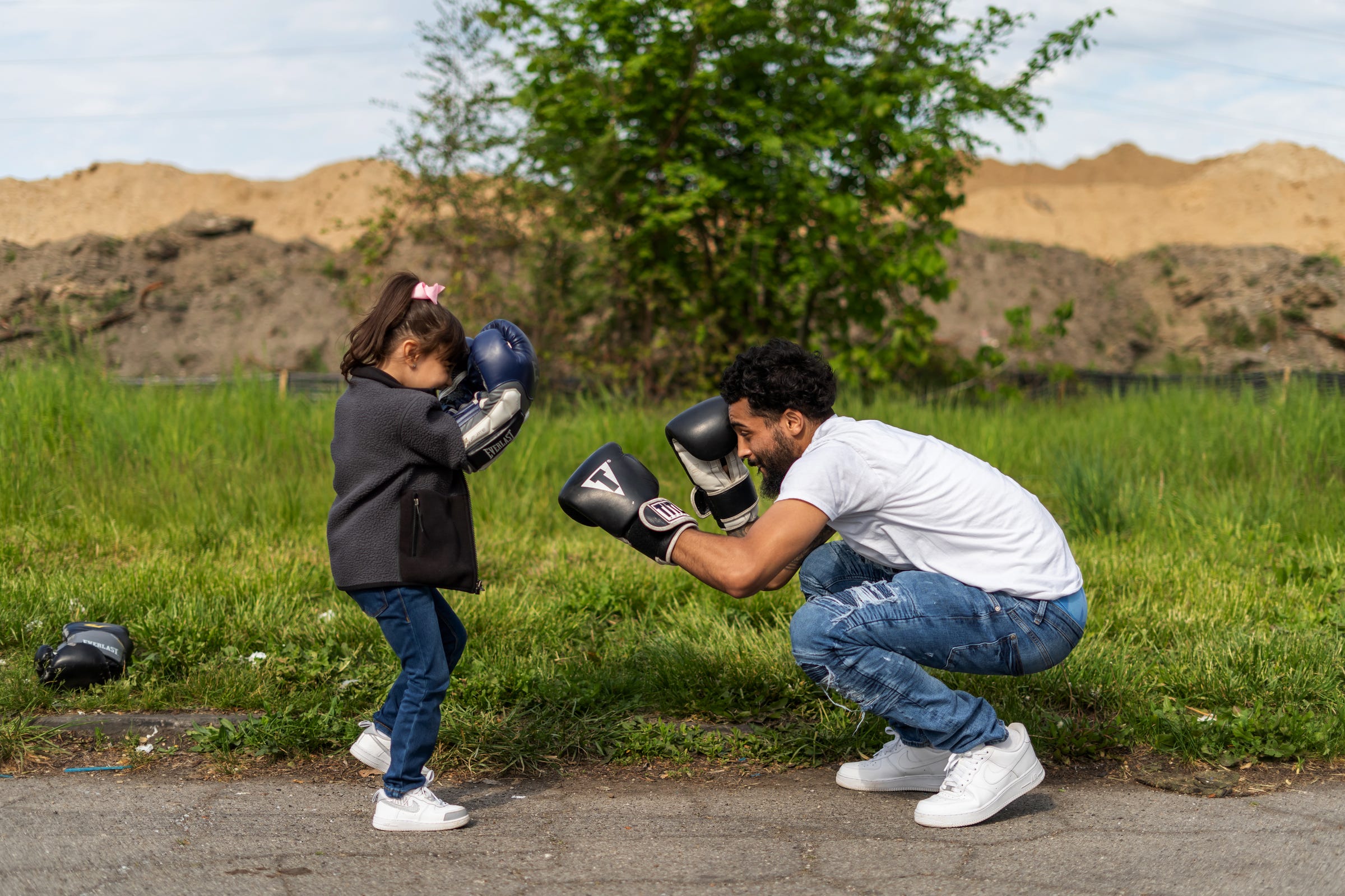 Dwayne Taylor, of Lincoln Park, puts on boxing gloves as his daughter Niyah Taylor looks to challenge him while waiting for people to show up for the start of a Pick Your Poison Detroit boxing event run by Taylor in Detroit's Delray neighborhood on Sunday, May 16, 2021.
