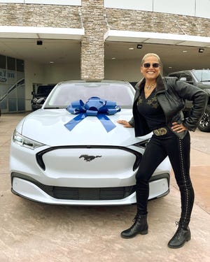 Dr. Sian "Leo" Proctor with her Ford Mustang Mach-E wrapped with a blue ribbon.