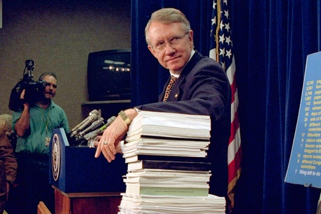 Senator Harry Reid, D-Nev., bersandar pada setumpuk dokumen yang berkaitan dengan reformasi keuangan kampanye selama konferensi pers Capitol Hill pada 3 Desember 1996, di mana kepemimpinan Demokrat untuk Kongres ke-105 diumumkan.